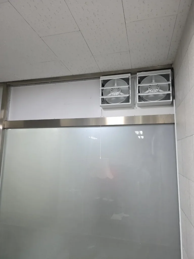 유리 칸막이 위쪽에 환풍기 두 대를 나란히 설치한 모습